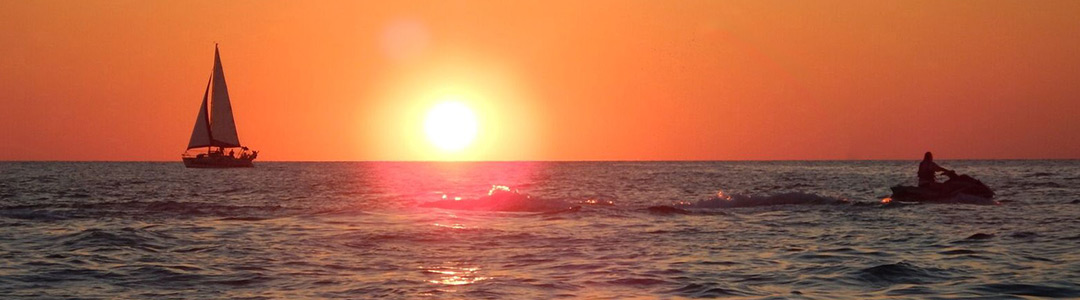 sunset behind a jet ski and sailboat